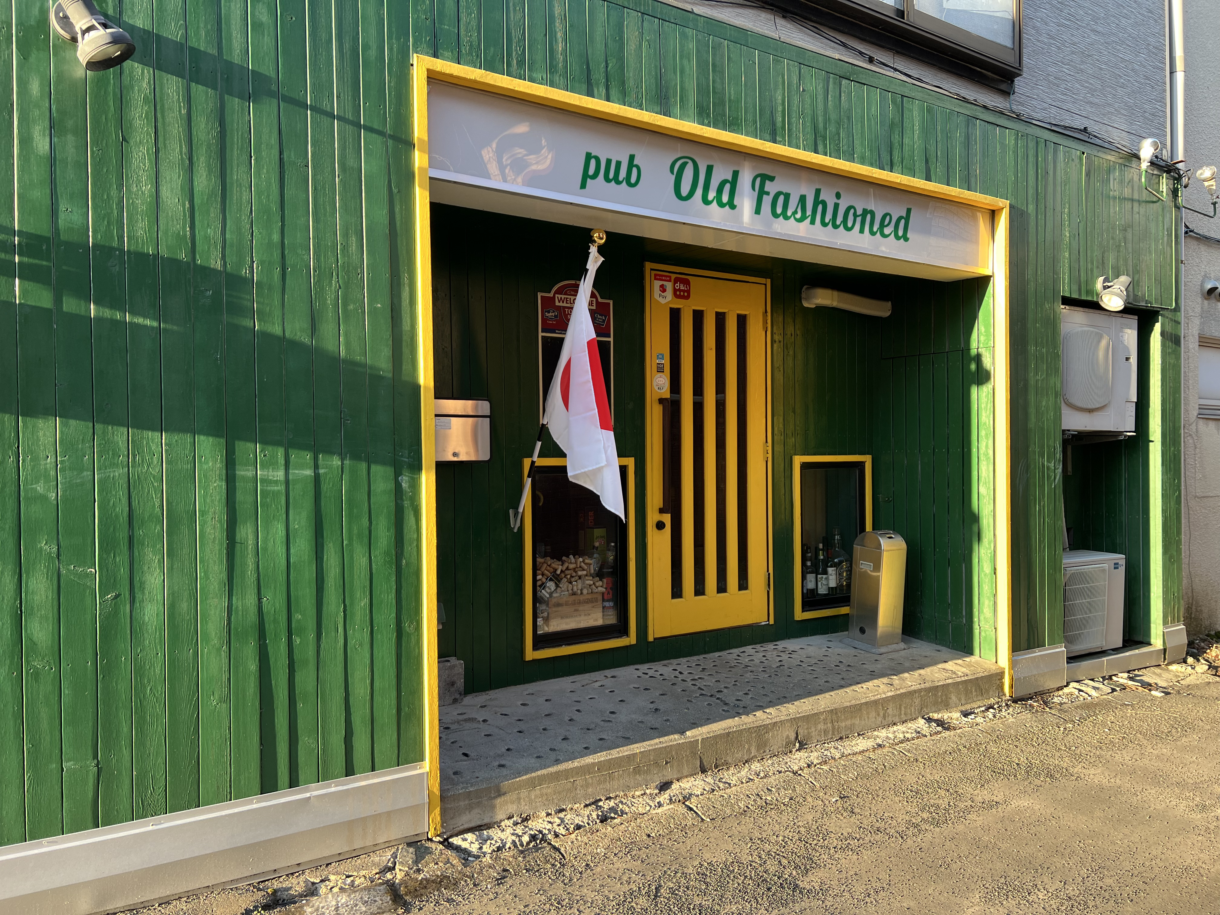 苫小牧の路地裏に面したパブの入口と店内の灯りが見える夜の外観